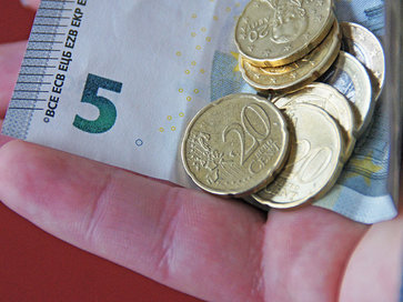 Symbolbild, Energie sparen, Handfläche darauf liegt ein Fünf-Euro-Schein und verschiedene Euromünzen