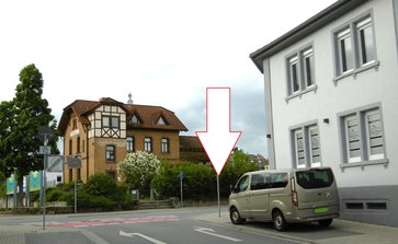 Rimbacher Bahnhof (Stationsgebäude) und rechts ehemaliges Gasthaus „Zum Goldenen Anker“, Ecke Staatsstraße/Friedrich-Ebert-Straße, Pfeil: Bombeneinschlag (Foto: Paul Kötter, Mai 2020)