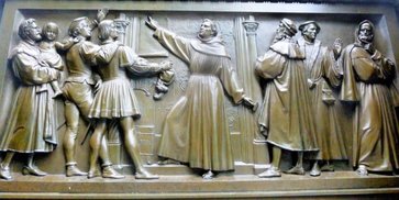 Relief am Lutherdenkmal in Worms (1868): Thesenanschlag Luthers vom 31.10.1517 Luther verherrlichendes Relief im Stil der Zeit: Luther selbst schlägt kraftvoll mit einem Hammer die 95 Ablassthesen an die Tür der Schlosskirche in Wittenberg. Umgeben ist er von Bürgern, Studenten und Theologen mit dem nachdenklichen Melanchthon (ganz rechts).